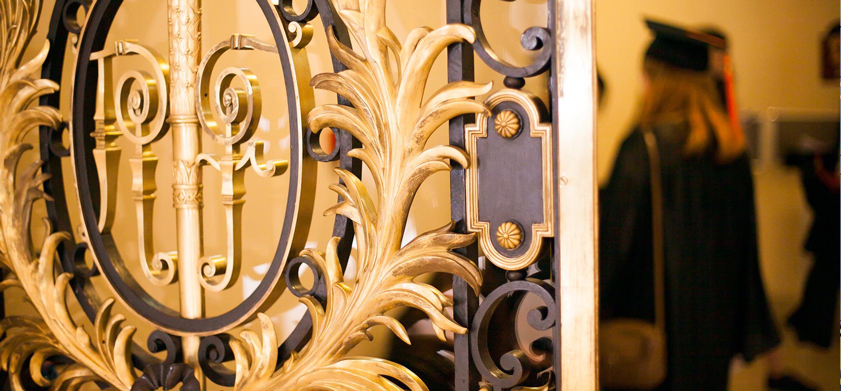 Photo des portes dorée de la Sorbonne avec une diplômée au loin.