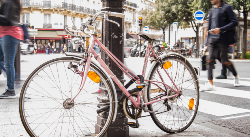 Vélo rose contre un poteau en pleine ville