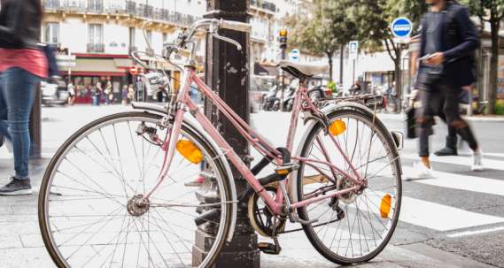 Vélo rose contre un poteau en pleine ville